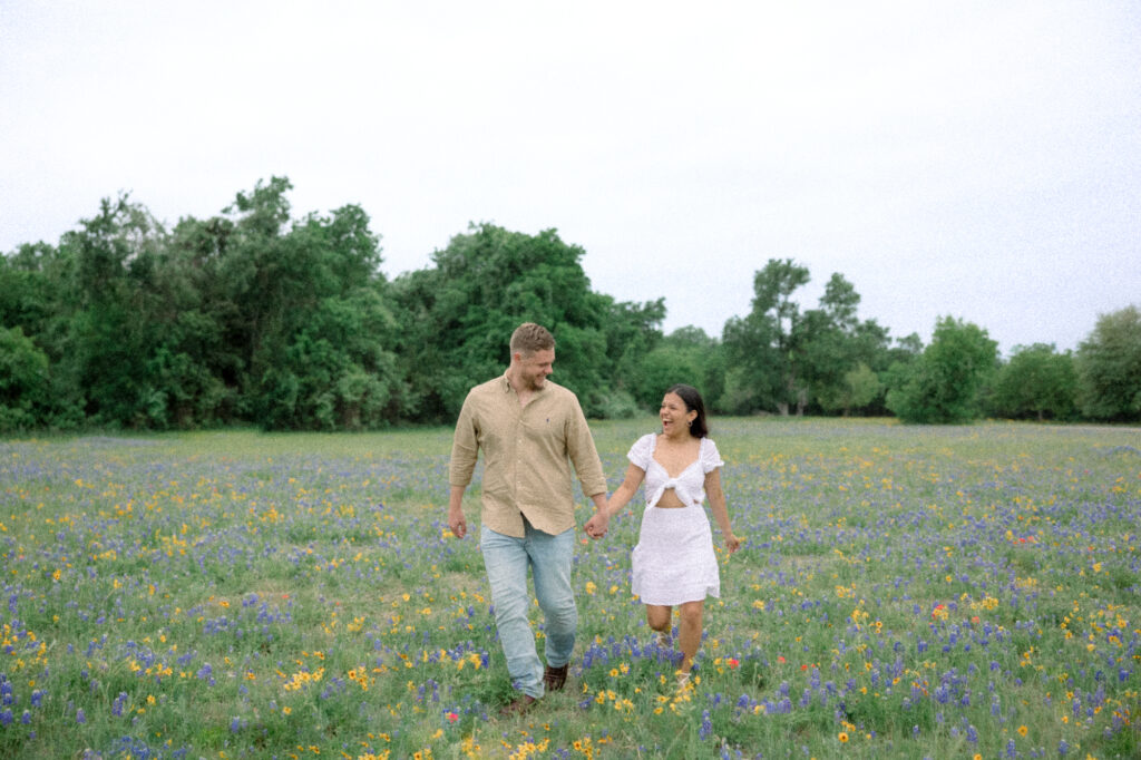 Running through a Texas bluebonnet field holding hands by Lois M Photography 