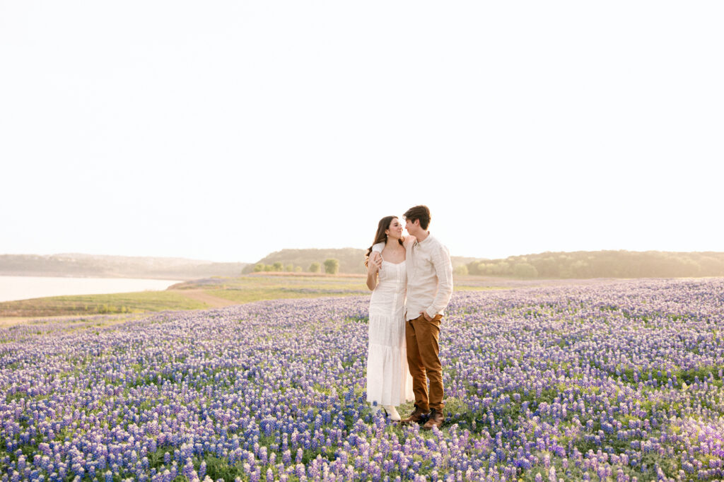 Engaged couple gazing into eachother's eyes in a bluebonnet field together at Muleshoe Bend. 