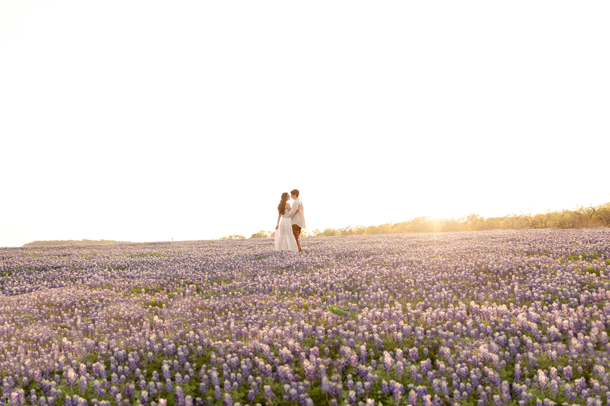 Engaged couple during sunset in the field of bluebonnets at Muleshoe Bend.