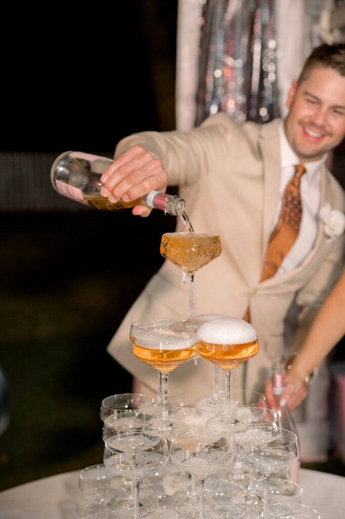 groom pouring champagne which is one of 2024 best wedding trends 
