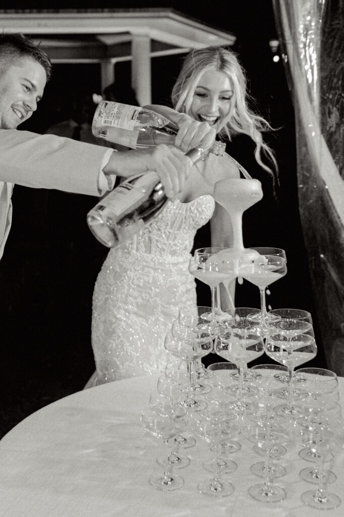 bride and groom pouring champagne for champagne tower 2024 