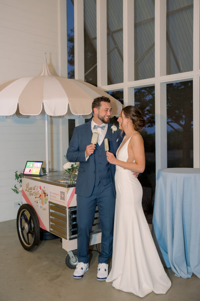 Bride and groom eating ice cream as a late night snack during their wedding reception, which is a 2024 wedding trend