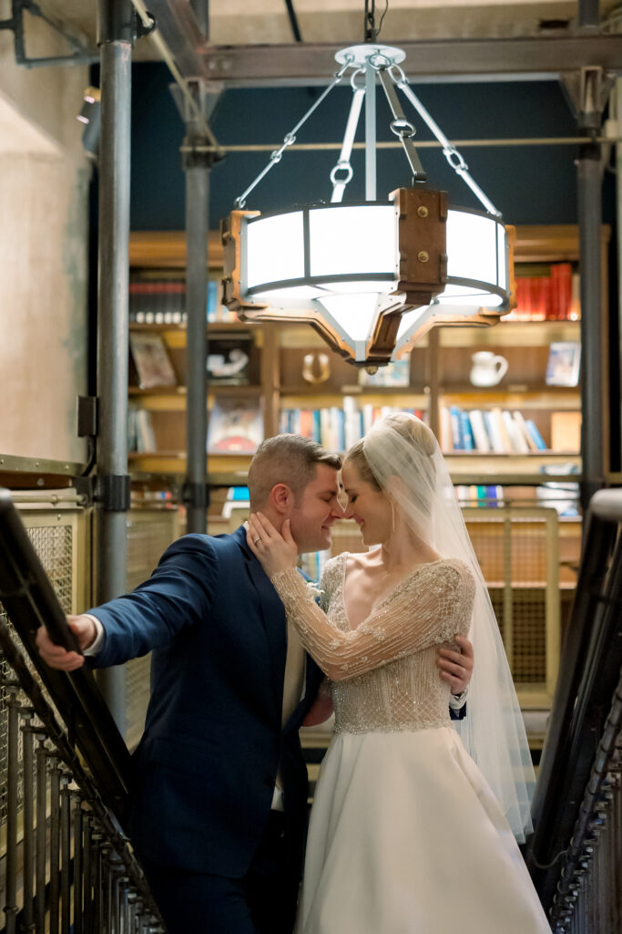 Bride and Groom embracing on stairs of Hotel Emma's Library Room. 