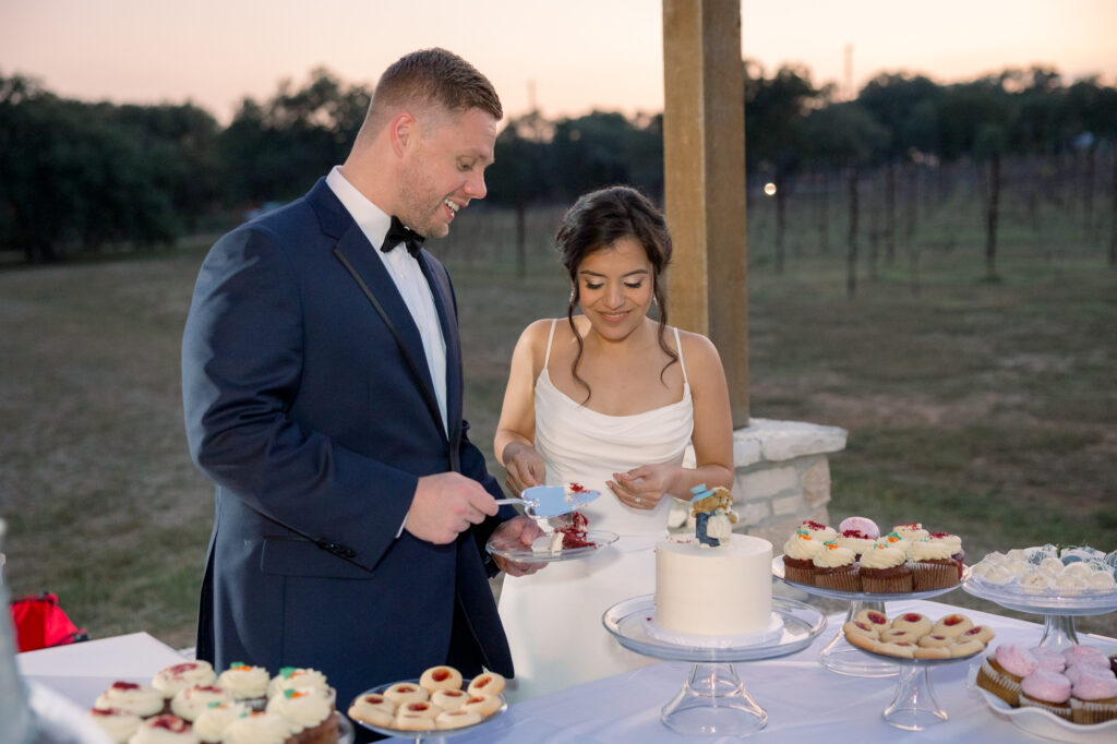 The bride and groom cutting their cake amongst other desserts at Jacob's Well Vineyard.