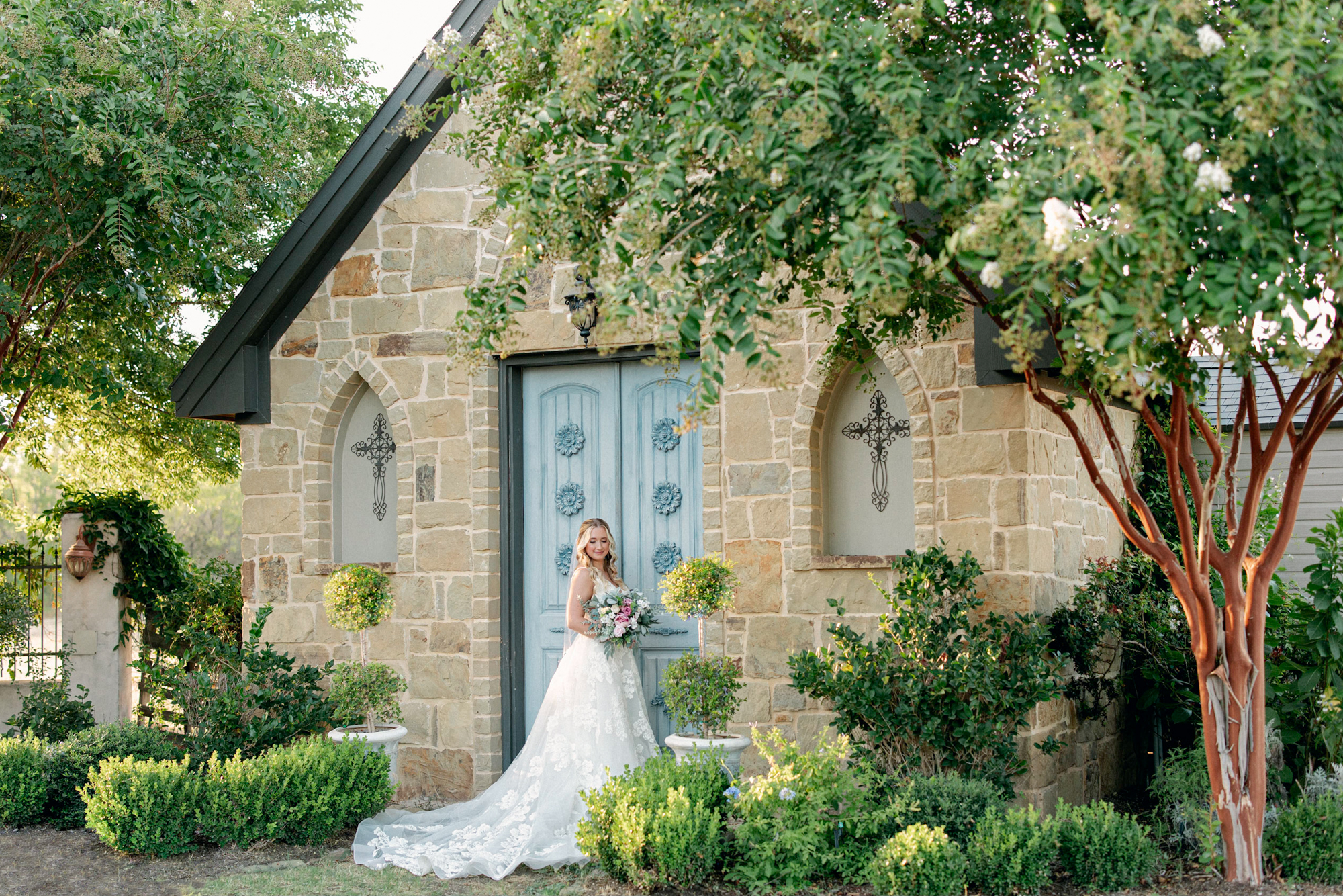 Bride in courtyard during bridal session by blue door at Thistlewood Manor and Gardens
