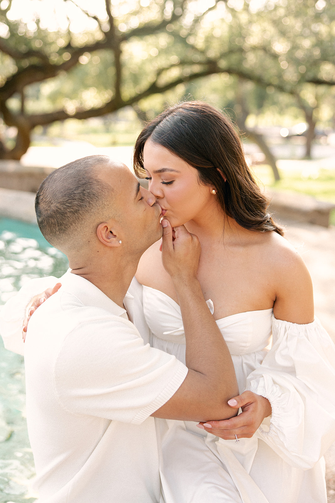 Engaged couple kissing by the fountain at The Mcnay Art Museum Grounds