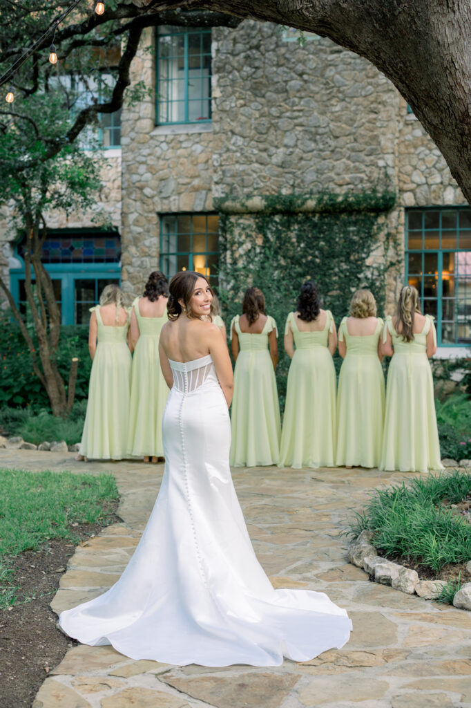 Bride smiling at the camera as she prepares to surprise her bridesmaids with a first look at the Veranda San Antonio