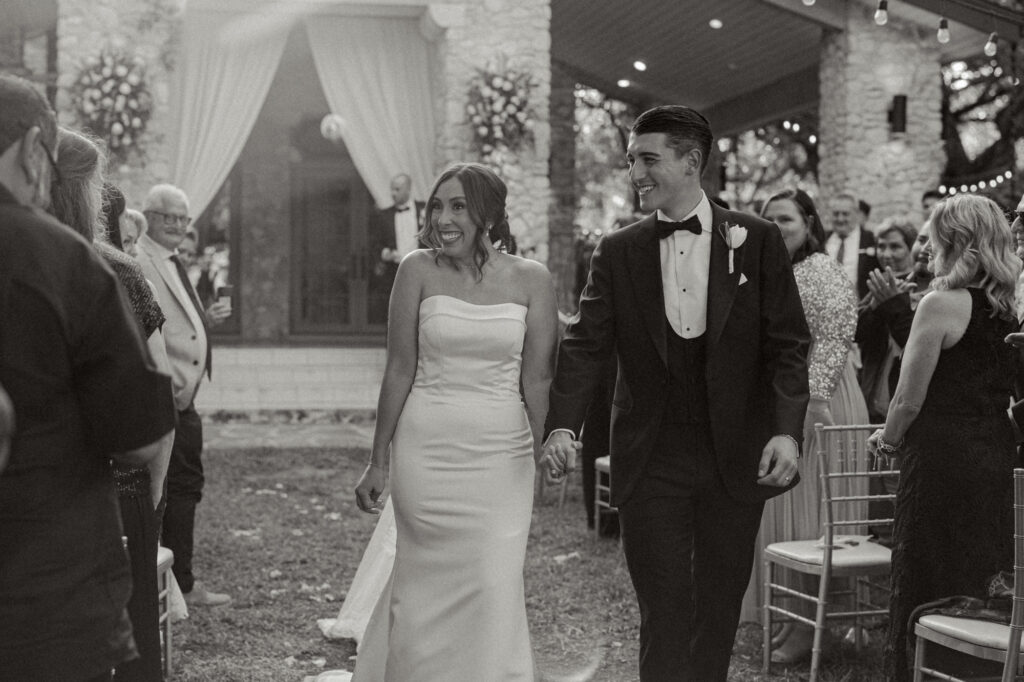 Bride and Groom joyfully smiling at guests during their recessional at the Veranda in San Antonio