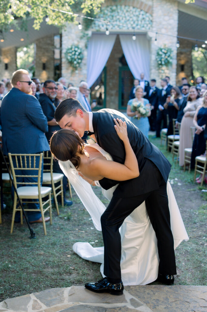 A romantic dip at the end of the aisle by bride and groom after their wedding ceremony completion at the Veranda 