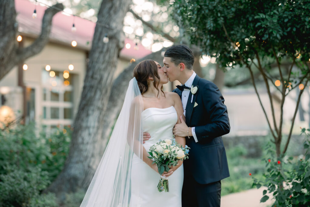 Bride and groom sharing a kiss during their newly wed portraits in the Courtyard at the Veranda in San Antonio