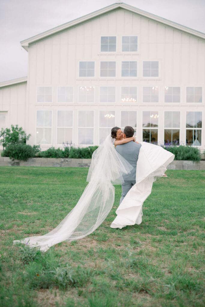 Groom carrying bride to Posey Meadows wedding reception