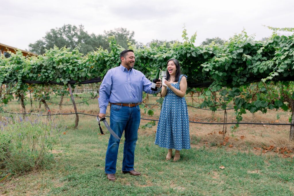 A newly engaged couple opening a bottle of champagne at William Chris Vineyards